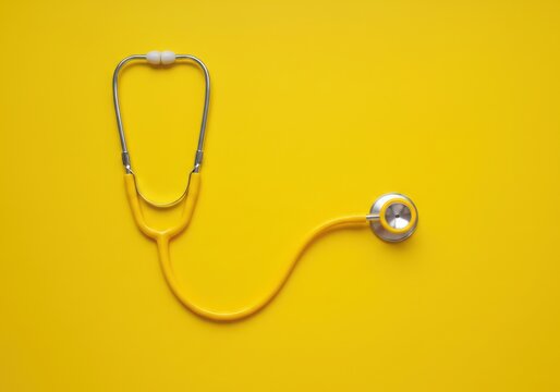 Yellow stethoscope on a yellow background - Powered by Adobe