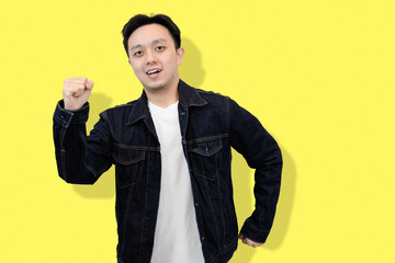 Joyful Asian Man in Denim Jacket running in yellow background