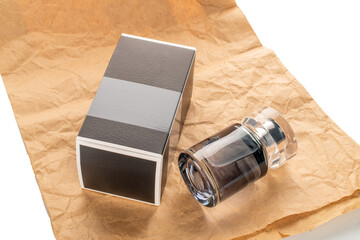 One bottle of perfume and paper packaging on kraft paper isolated on white background, close-up.