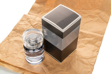 One bottle of perfume and paper packaging on kraft paper isolated on white background, close-up.