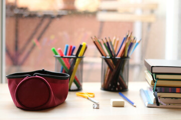 School supplies on a table. Pencils, markers, a ruler, erasers, a notebook, a pen, erasers, and a...