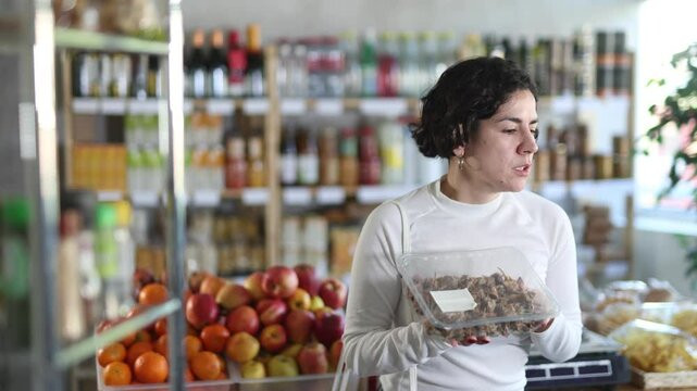 Adult woman buyer chooses purple dye murex or spiny dye murex (Bolinus brandaris) in grocery store