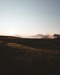 Sunrise mist over alpine meadow and silhouetted peaks beneath a clear, expansive sky