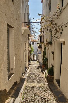 Empty narrow streets of Cadaqu&eacute;s, Spain, with white houses and clear blue sky. The peaceful historic town center is beautifully captured without any people, highlighting its charm and tranquility.