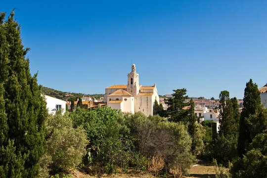 Charming narrow streets of Cadaqu&eacute;s, Spain, with white church on the hill, houses and vibrant blue sky, showcasing the historic Mediterranean coastal town&rsquo;s beauty and traditional architecture