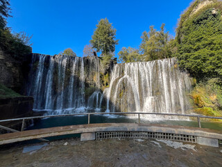  Bright waterfall surrounded by lush greenery and blue sky