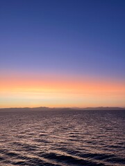 Golden sunset view from a cruise ship at sea. Calm ocean waters reflect warm tones as the sun dips below the horizon, creating a peaceful and scenic maritime atmosphere.