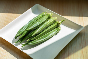 A plate of fresh okra on the table. Fresh seasonal ingredient. 