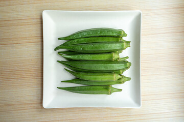 A plate of fresh okra on the table. Fresh seasonal ingredient. 