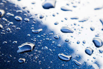 Water drops on blue powder coated car surface, focus view.