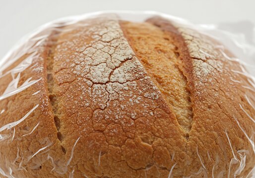 Close-up of a freshly baked loaf of bread wrapped in plastic for freshness