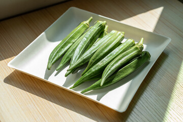 A plate of fresh okra on the table. Fresh seasonal ingredient. 