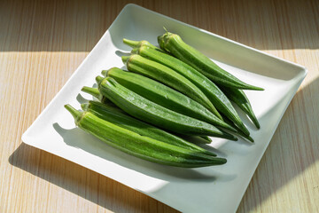 A plate of fresh okra on the table. Fresh seasonal ingredient. 