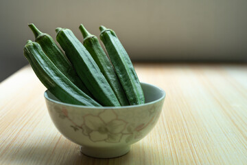 A plate of fresh okra in a bowl on the table. Fresh seasonal ingredient. 