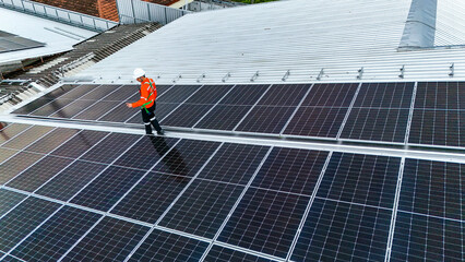 Solar power technician inspecting rooftop solar panels, performing maintenance and installation of...