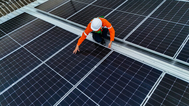 Solar power technician inspecting rooftop solar panels, performing maintenance and installation of renewable energy systems for a sustainable future.