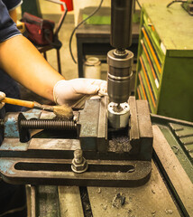 Close-up of metal drilling process using an industrial drill press machine in workshop. worker...