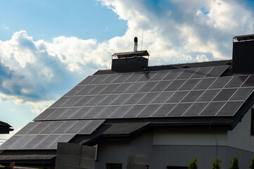 Solar panels capture sunlight on a home's roof, showcasing renewable energy technology against a blue sky with fluffy clouds