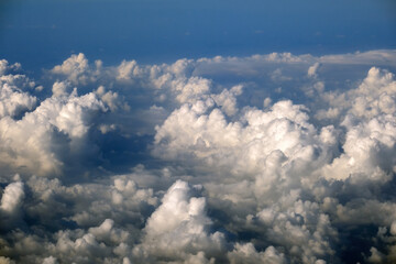 Cloudy sky, from airplane window point of view. View from above at high altitude of dense puffy...