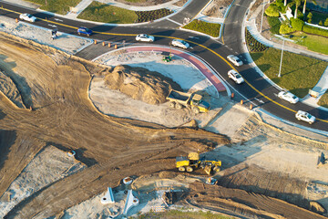 Driving traffic cars at roundabout intersection under construction. Building traffic circle on...