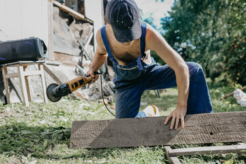 male builder restores old wooden house, replacing boards