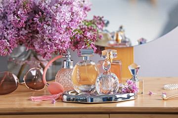 Bottles of perfumes, accessories and lilac flowers on wooden table