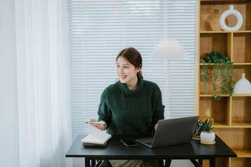 Cheerful woman using laptop at home. Girl working on computer. Blogger, writer, journalist or...