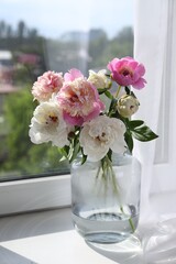 Bouquet of beautiful peonies in vase on window sill indoors