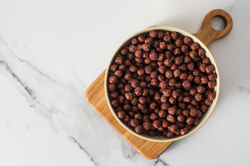 Bowl of chocolate round flakes on kitchen counter for breakfast. Dry breakfast. Copy space