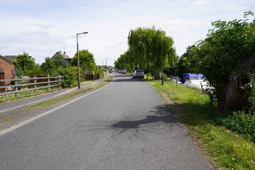 Nottinghamshire, England - June 20 2025: Quiet residential street curving along a waterway, mixing...
