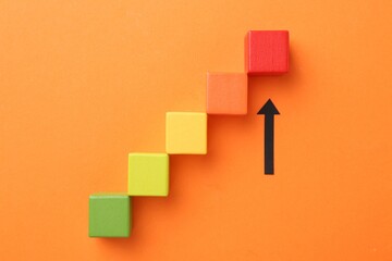 Maximum. Arrow pointing at colorful cubes on orange background, top view