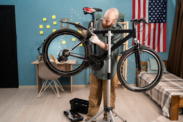 Bearded man fixing wheel on a bicycle during a repairment working at home