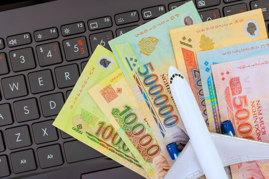 .Various Vietnamese dong banknotes miniature airplane placed on laptop, symbolizing financial aspects of travel planning