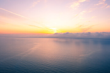 Aerial View of Golden Sunset Over Calm Ocean with Fog Layer Spreading Across Horizon