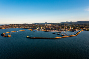 Aerial view of Dun Laoghaire Harbour with sailboats, town, and Dublin mountains during a glowing...