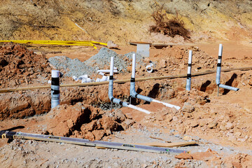 Wastewater plumbing pipes are positioned in freshly excavated area at construction site during work...