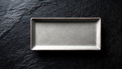 Gray rectangular plate with crackled texture on a dark textured surface.