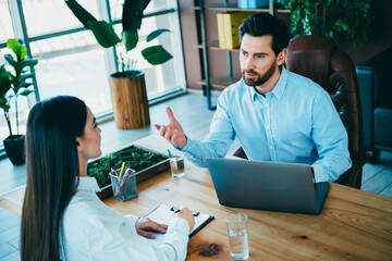 Professional colleagues having a productive discussion in a modern office setting with laptops and documents