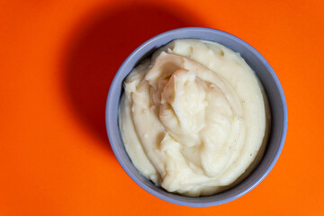 Creamy mashed potatoes served in a bowl on vibrant orange background