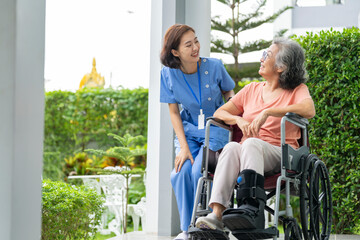 A senior woman with a leg injury laughs with her caregiver during a rehabilitation session. A...