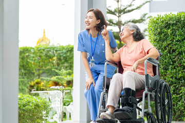 A senior woman with a leg injury laughs with her caregiver during a rehabilitation session. A...