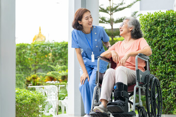 A senior woman with a leg injury laughs with her caregiver during a rehabilitation session. A...