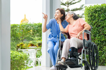 A senior woman with a leg injury laughs with her caregiver during a rehabilitation session. A...