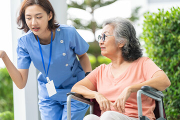 An empathetic caregiver crouches to listen to a senior woman in a wheelchair, demonstrating respect...