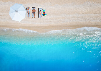 Top view of a happy family on lounge chairs at summer vacations enjoying the the beautiful beaches of Greece, Ionian Sea