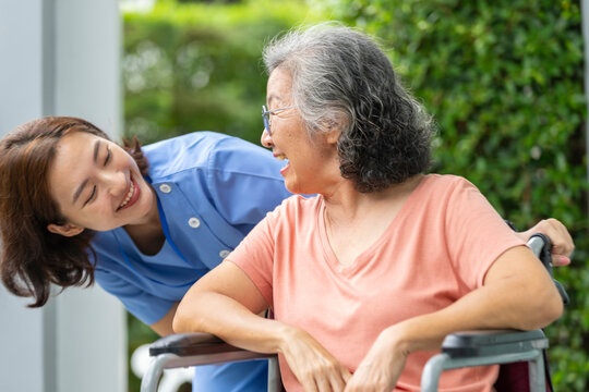 An empathetic caregiver crouches to listen to a senior woman in a wheelchair, demonstrating respect and building trust. A concept for patient-centric communication and holistic health.