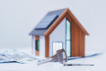 Miniature home with solar panels, keys and deeded dollars. Real estate deal concept, eco-friendly...
