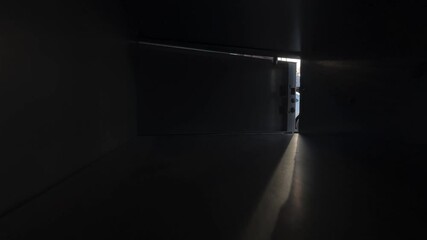 Point-of-view shot from inside a parcel locker as a man opens the compartment and retrieves a package. Urban delivery concept with self-service pickup and modern logistics.