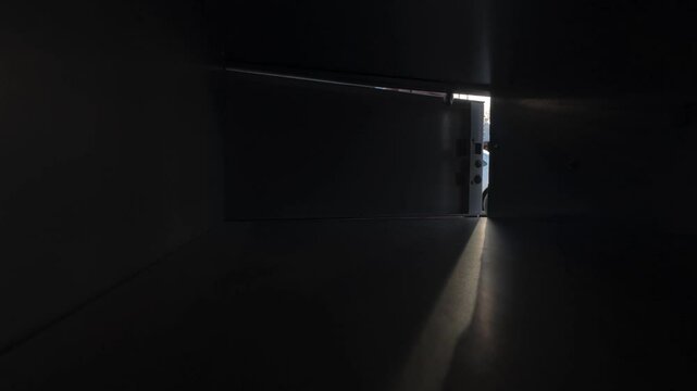 Point-of-view shot from inside a parcel locker as a man opens the compartment and retrieves a package. Urban delivery concept with self-service pickup and modern logistics.