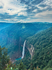 Nohkalikai Falls plunges dramatically from lush cliffs into a turquoise pool below, framed by dense...